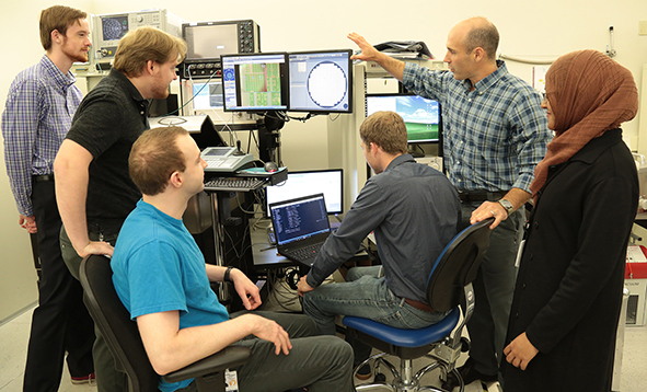 Prof. Nate Cady in a lab in front of a computer with five students