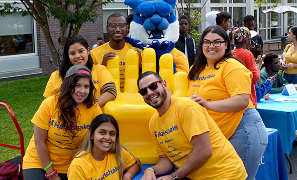 walter the wildcat surrounded by a group of students wearing yellow shirts