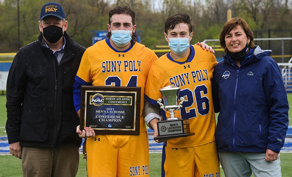 two lacrosse players with president and woman holding trophy and plaque