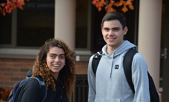 two students smiling for a photo outside