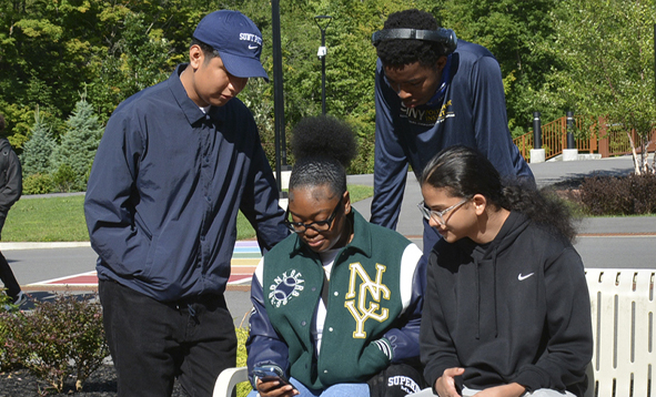 Four college students looking at a cell phone